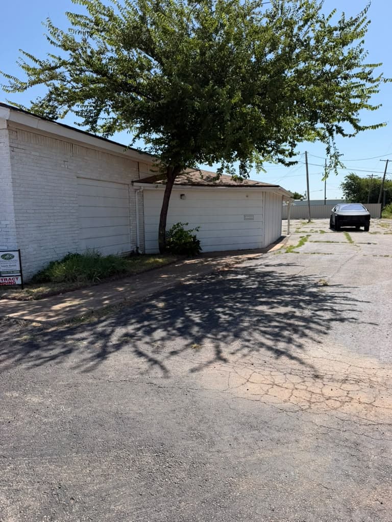 The side entrance of the building, shaded by a tree